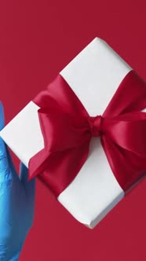 Gift with Red Ribbon Being Presented by Hands