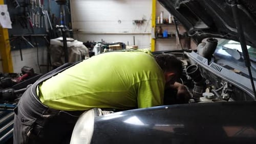 Automechaniker für Erwachsene, die das Auto in der Werkstatt warten, professioneller Mechaniker, der unter der Motorhaube arbeitet