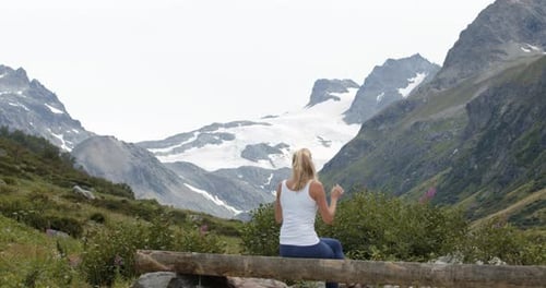 Young sporty woman having a breake hiking in the mountains and enjoying the view of the alpine mount