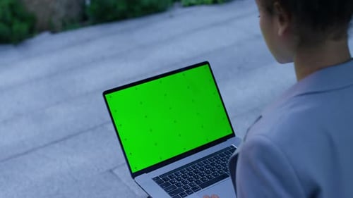 Woman Looking at Green Screen Laptop Outdoors