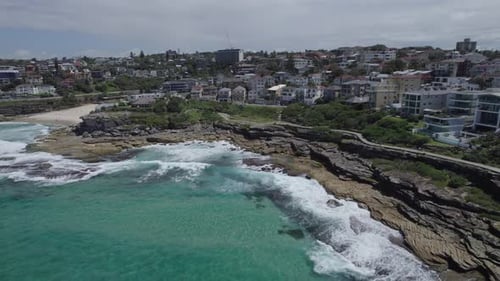 Foamy Splashing On The Rocky Shoreline Of Tamarama Point In New South Wales, Australia. Aerial Drone