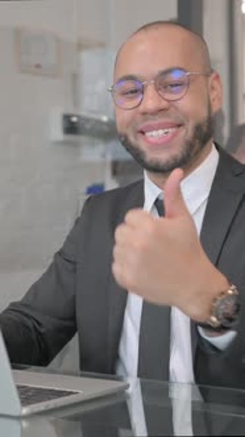 Young Businessman Gives Thumbs Up Working at Desk