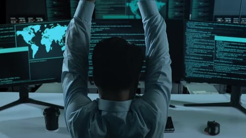 Back View Of Tired Asian Man Stretching While Write Code With Multiple Computer Screens In office