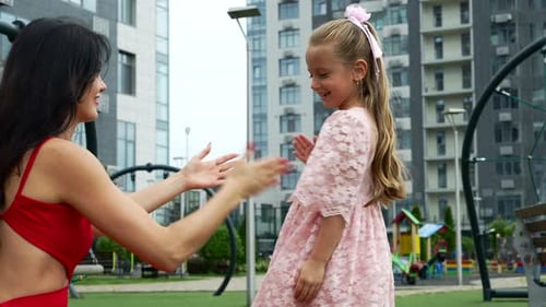 Joyful Moments of Mother and Daughter Playing in Urban Park During Sunny Day