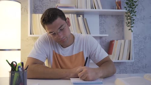 Man Studying and Writing in a Notebook at Home