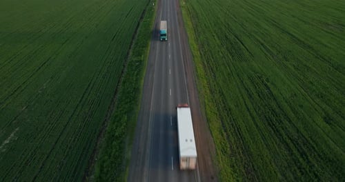 Two Trucks with a Semitrailer are Driving Along the Highway Aerial Footage