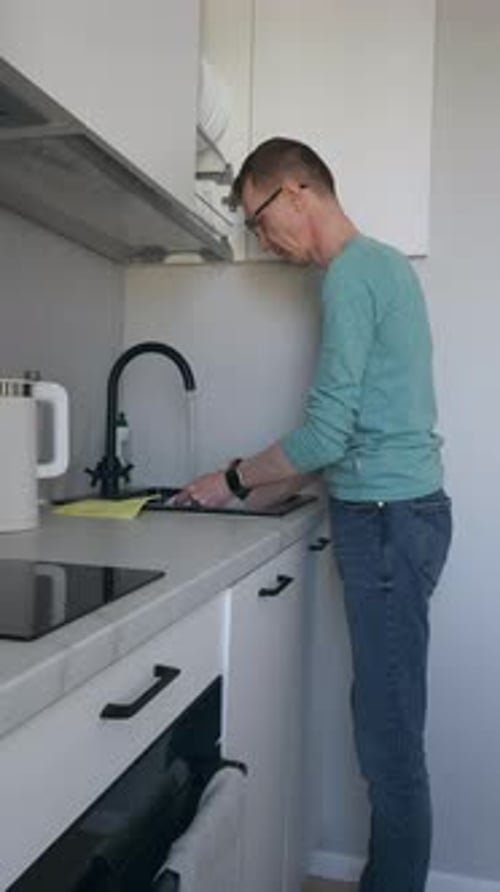 Man Washing Dish at Sink in Home Kitchen