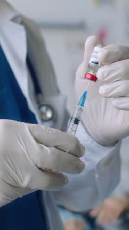 Medical Professional Preparing Injection from Vial Close Up