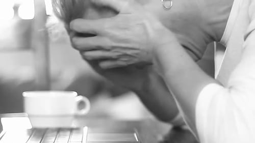 Woman with Hands Covering Face Next to Laptop