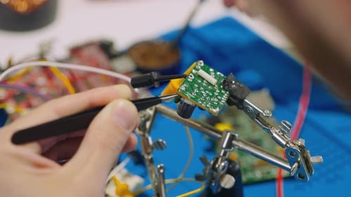 Man is Soldering in a Repair Shop Concentrated Technician Busy Repairing at Workshop