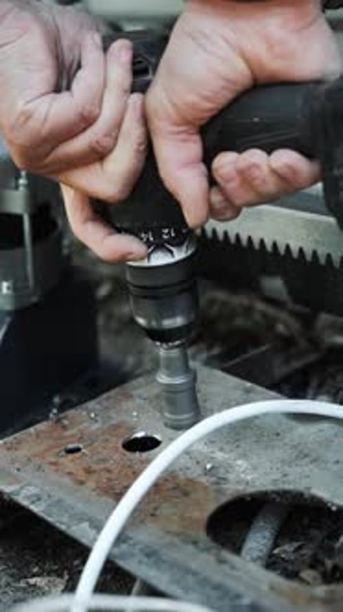 Close up of Drill bit Drilling into metal Pipe. Drilling a hole in the square steel pipe