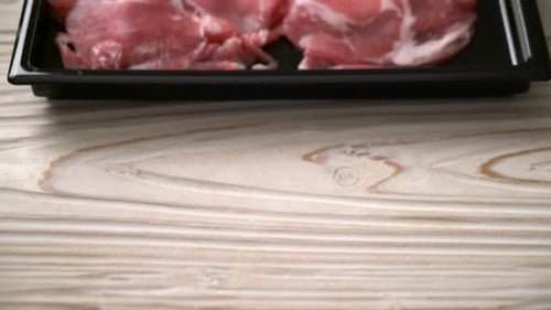 Thinly Sliced Raw Pork Presented on Black Tray