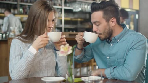 Attractive Young Man and Woman are Sitting Talking at Cozy Coffee Shop.