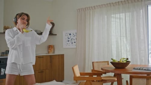 Woman Singing Into a Banana Microphone at Home