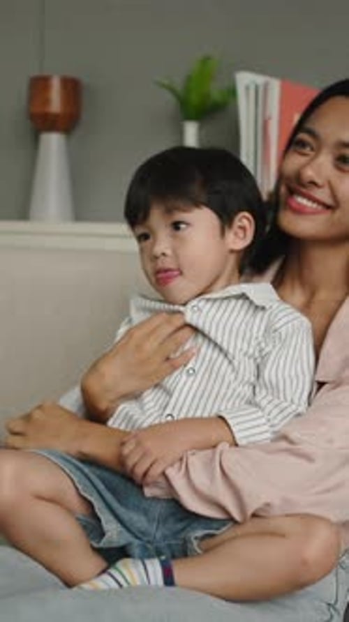 Happy Boy Sitting on Mom's Lap Indoors