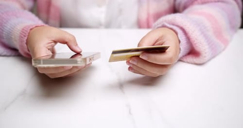 Close-up woman's hand holds a smartphone and use a mockup Bank credit card for online shopping servi