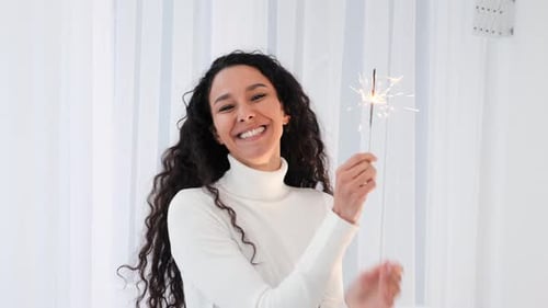 Happy Woman Smiles with Sparkler Indoors