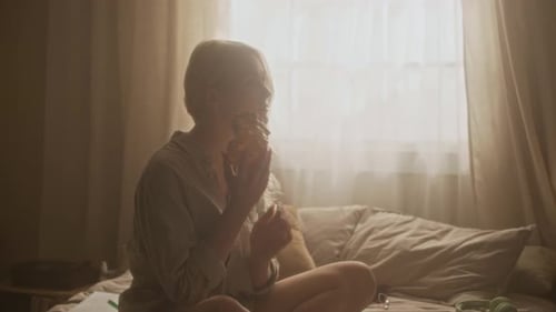Femme délicate écoutant le son des coquillages sur le lit sous la lumière du matin