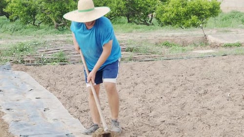 Farmer Man with a Hoe Plowing the Land on an Ecological Farm in Catalonia Spain