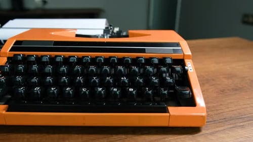 Briefe schreiben mit einer orangefarbenen Retro-Vintage-Schreibmaschine