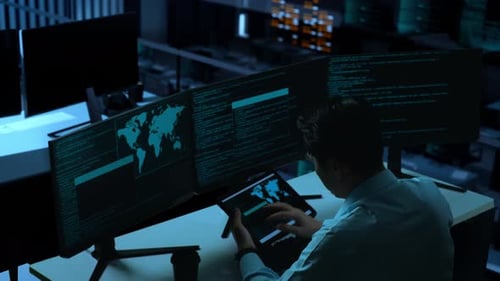 Asian Man Working With Tablet While Write Code With Multiple Computer Screens In office