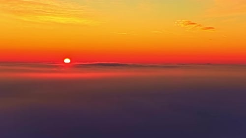 Aerial View of Fiery Sunset Over a Sea of Clouds