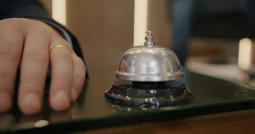 Closeup of Businessman's Hand Rigning Bell at Hotel Reception Desk