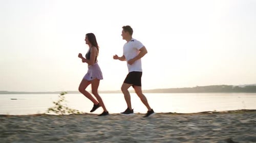 Couple Running Together on a Sandy Beach at Sunrise