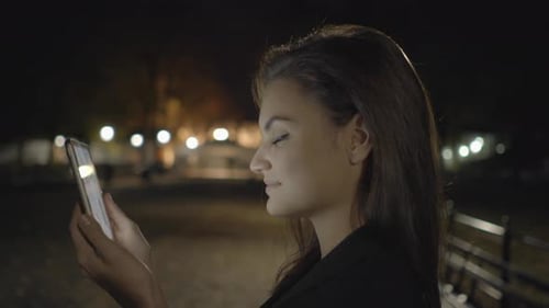 Young Woman Using Tablet Computer In The Park At Night