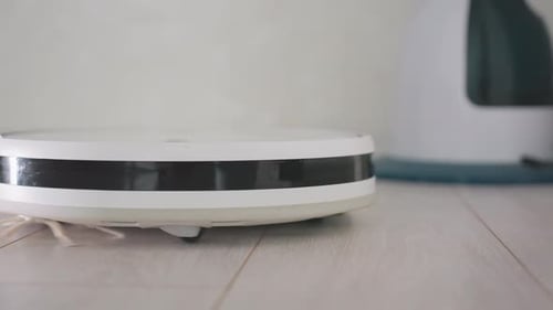 Robot Vacuum Cleaner Sweeping on Wood Floor Indoors