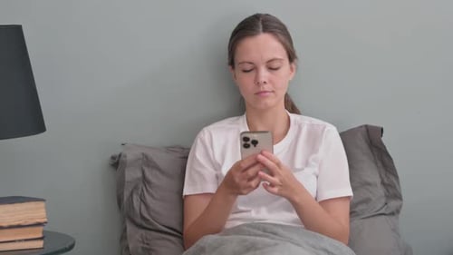 Woman Uses Phone in Bed