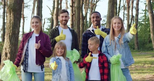 Smiling Volunteers Posing in Forest with Trash Bags