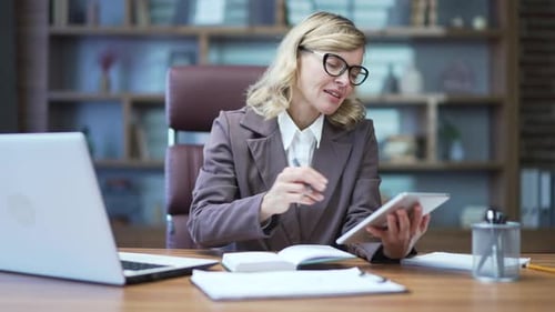 Woman Uses Tablet and Notepad in an Office
