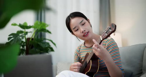 Woman Sings and Plays Ukulele on Couch