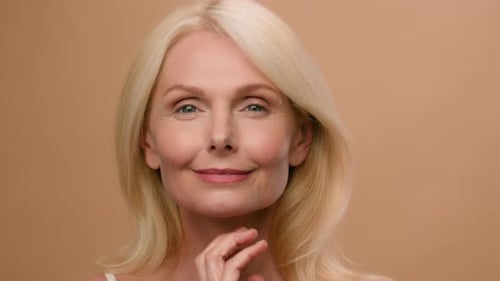 Beautiful Caucasian Mature Senior Middleaged Woman in Beige Studio Sensual Lady Touch Face Neck