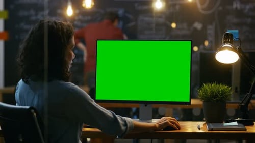 Beautiful Female Office Employee at Her Desktop Works on a Mock-up Green Screen Personal Computer.