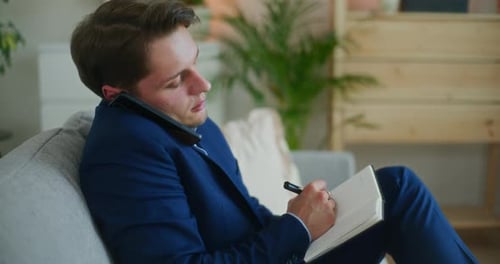 Un homme d'affaires prend des notes au téléphone