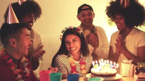 Happy Woman Blowing Candles of a Birthday Cake with Friends