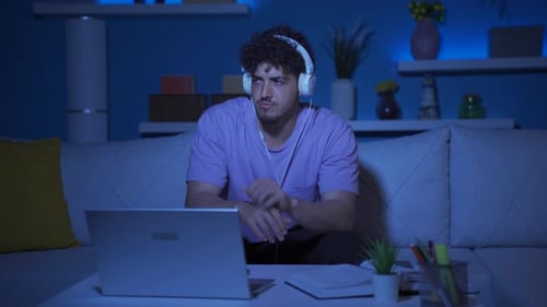 Depressed young man at home at night, bored and pensive.