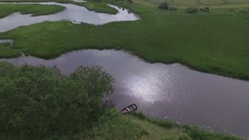 Wooden Boat In A Winding River On A Cloudy Summer Day. Aerial Pedestal-Up Shot