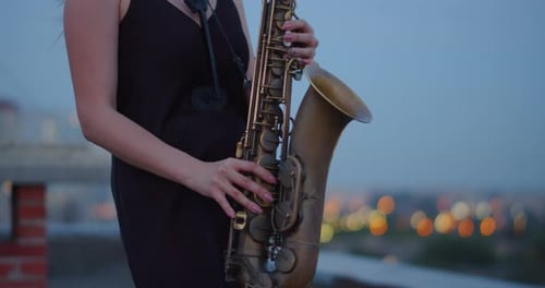 Woman Plays Saxophone on Rooftop at Night