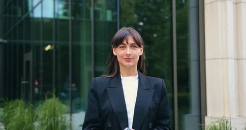 Confident Young Brunette Businesswoman Standing Outdoors on a Busy City Street Looking Directly at