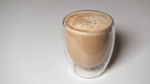 Close Up Pouring Milk Into Transparent Double Wall Glass Cup of Black Coffee Adding Creamer to