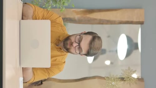 Man With Glasses Smiles at Laptop Desk