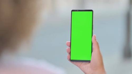 Young African Woman holding Phone with Green Screen Outdoor