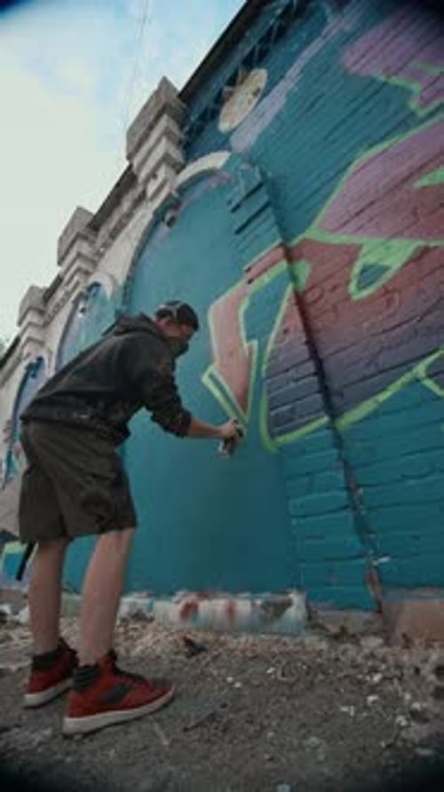 Straßenkünstler zeichnet Pfeilform auf Graffiti-Tag an der Wand