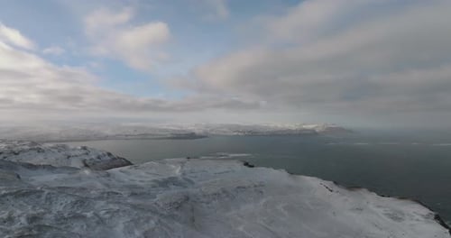 scenic icelandic landscape view on rocky shore ocean, snowy mountains and green grass