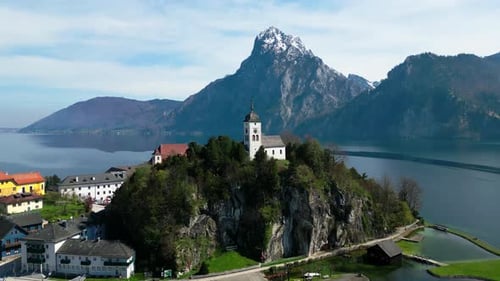 Eine ruhige Kirche auf einer Klippe in Österreich mit einer majestätischen Bergkulisse, Luftaufnahme