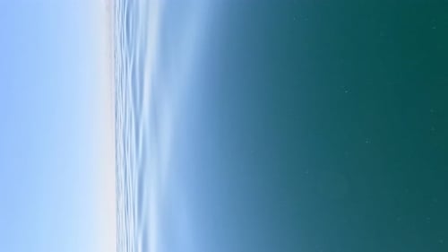 Vertikale Luftaufnahme der Meerwasseroberfläche: Kamera fliegt über klares Meerwasser, Sonnenblendung, abstrakt