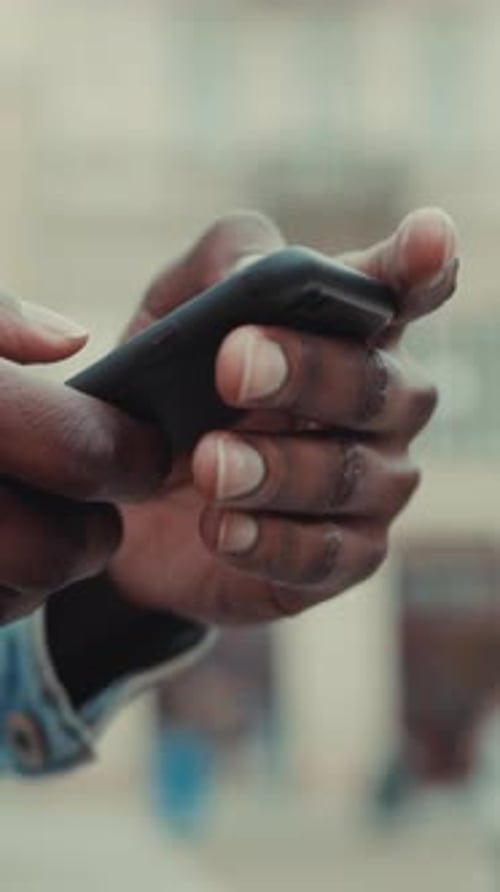 Adult Using Black Cellphone in City Environment